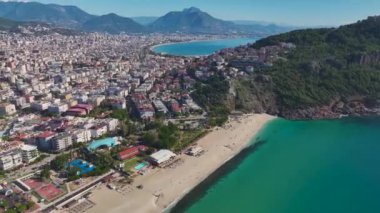 Alanya 'da nefes kesici bir kumsalın insansız hava aracı görüntüleri. Turkuaz su, yumuşak kum ve parlak mavi gökyüzü..