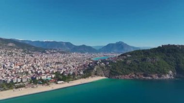 Alanya 'da deniz manzaralı bir sahil manzarası. Gök mavisi dalgalar kıyıya vuruyor. Huzurlu bir sahil cenneti yaratıyor..