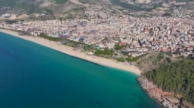 Alanya 'nın parlak turkuvaz suyu, pürüzsüz kum ve güneşli bir günde açık mavi gökyüzü olan kumsalının insansız hava aracı görüntüleri..