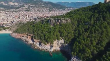 Alanya 'nın güzel sahil şeridinin havadan çekilmiş görüntüsü. Parlak mavi deniz dalgaları altın kumsala dokunuyor..