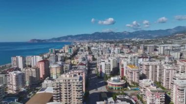 Sakin deniz sularına tepeden bakan şehir canlılığı.