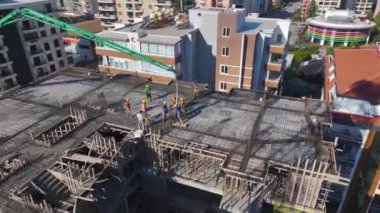 İşçiler beton döküyor ve metal çerçeveler kuruyorlar.