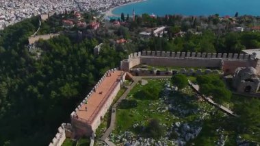 Alacakaranlıkta Alanya Kalesi 'nin güzelliğine tanık olun. Akdeniz alacakaranlık gökyüzünün renklerini yansıtıyor..