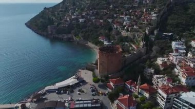 Alanya 'nın limanında taş duvarlar ve görkemli bir dağ zeminiyle çevrili ikonik kırmızı antik kuleyi keşfedin..
