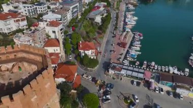 Alanya 'nın limanındaki kırmızı kuleyi ziyaret edin, taş duvarlar ve mükemmel bir çekim için çarpıcı bir dağ arkaplanı..