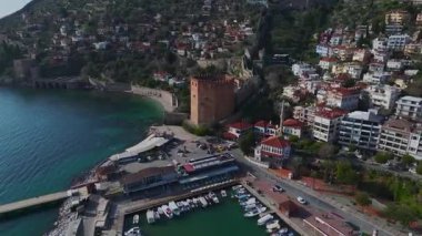 Alanya 'nın tarihi kırmızı kulesini keşfedin, taş duvarlar ve liman manzaralı nefes kesici bir dağ manzarası.