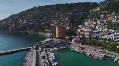Limandaki Alanya 'nın kırmızı kulesine hayran kaldım. Duvarlarla çerçevelenmiş ve arka planda dramatik bir dağ manzarası var..