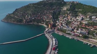Alanya 'nın limanında taş duvarlar ve görkemli bir dağ zeminiyle çevrili ikonik kırmızı antik kuleyi keşfedin..