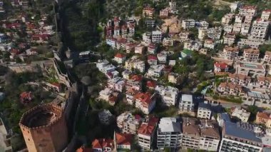 Alanya 'daki kırmızı kuleyi keşfedin, taş mimarinin bir karışımı, canlı liman sahneleri, ve dingin bir dağ arkaplanı.