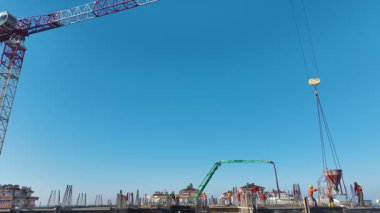 Aktif inşaat alanı. Beton döken ve çeliği kaldıran işçilerin hava görüntüleri.