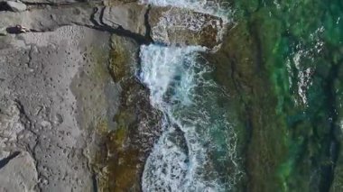 Kayalar ve sakin dalgalar. Sakinleştirici ve sakin bir deniz manzarasının hava görüntüleri..