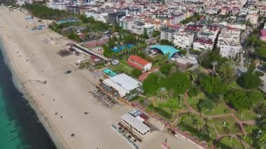 Beyaz kum, güneşli bir gün ve şehir manzarası. Rüya gibi bir sahilin havadan çekilmiş görüntüleri..