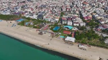 Altın kum, mavi deniz ve şehir silüeti. Nefes kesici bir kumsalın hava görüntüleri..