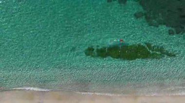 Açık denizde yüzen bir adam. Barışçıl bir tropikal manzaranın hava görüntüleri..