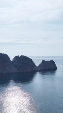 Okyanus kayaları ve köpüklü dalgalar. Manzaralı deniz manzarasının dikey görüntüleri.