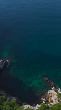 Kaya kıyısı ve gür ağaçlar. Çarpıcı bir kıyı manzarasının dikey görüntüleri.