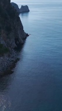 Taş plajı ve mavi su. Sakin doğa kaçışının dikey görüntüleri.