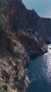 Kaya ve mavi su. Huzurlu ve resimli bir deniz manzarasının dikey görüntüsü.
