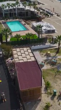 Çeşitli Etkinlik Alanlarına sahip tam donanımlı bir plajın dikey videosu, Yukarıdan Yakalandı, Yoğun bir Tatil Noktası Gösteriliyor