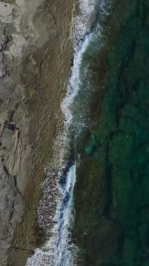 Kum ve deniz kontrastı. Nefes kesici bir kıyı manzarasının dikey görüntüsü.