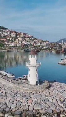 Limandaki Uzun Beyaz Deniz Feneri 'nin dikey videosu. Yukarıdan Yakalandı, Okyanusa ve Gökyüzüne Baktı.