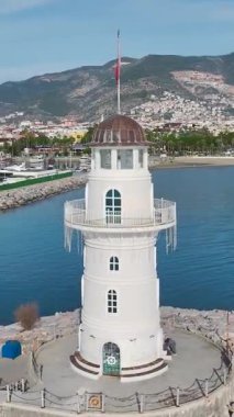 Güneş doğarken havadan deniz feneri. Sakin bir sahil sabahının dikey görüntüsü.