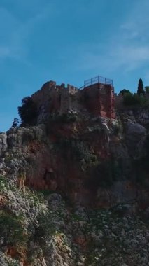 Havadan yüksek uçurum ve turkuaz deniz. Çarpıcı bir kıyı manzarasının dikey görüntüsü.