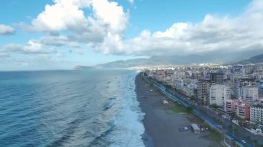 Kıyı şeridi fırtınalı gökyüzü altında dönüşür..