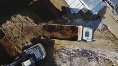 Kazıcı toprağı çöp kamyonuna taşır.