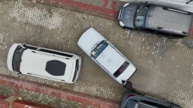 Otoparkta beyaz arabayı elle hareket ettiren kişi..