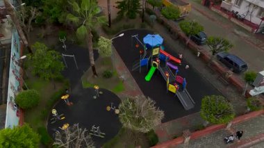 Çocuklar sallanırken, yetişkinler oyun alanında gözetmenlik yapıyor..