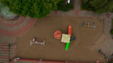 Turuncu spiral kaydırak ve yeşil düz kaydıraklı oyun alanı.