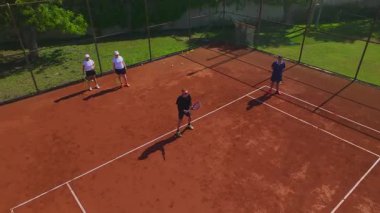 Kırmızı kil sahada atletler yan yana talim yapıyor.