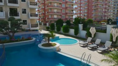 Yaz ışığında boş şezlongları olan mavi su havuzu.