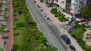 Yeşil park ve kumlu sahil arasındaki yolda bir sürücü var..