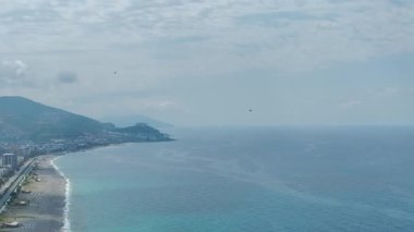 Dalgaların ve kayaların yanında helikopteri olan mavi helikopter pisti.