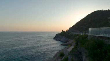 Dalgaların ve kayaların yanında helikopteri olan mavi helikopter pisti.