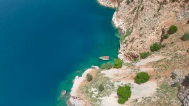 Deniz manzaralı yarımada, yelkenli yelkenli, hava görüntüleri kıyı şeridi, kayalıklar ve güneşli koşullarda mavi suyu gösteriyor.