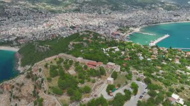Korsan dizaynlı büyük gemi kıyı şeridine yakın yelkenli, hava aracı görüntüleri yolcuları ve turkuaz denizi gösteriyor.