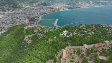 Turist korsan gemisi uçurumlardan geçiyor. Hava aracı görüntüleri güvertede, sahil şeridinde ve açık deniz suyunda insanların olduğunu gösteriyor.