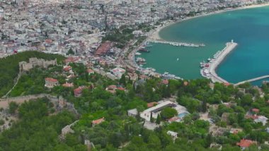 Yarımada denize açılıyor, korsan gemisi geçiyor, hava görüntüleri engebeli uçurumlar, turkuaz su ve görünür turistler gösteriyor.