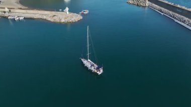 İHA görüntüsü, limana demirlemiş gemilerle dolu bir yelkenlinin girişini vurguluyor..