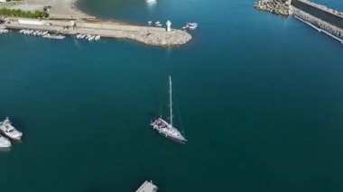 Mavi gökyüzünün altında tek başına yatların sıralarına yaklaşan bir geminin yukarıdan görünüşü.