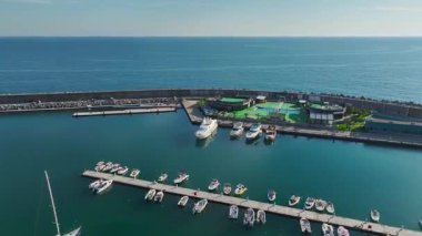 Yelkenliler, katamaranlar ve yatlarla dolu zarif bir limanın tepeden tırnağa insansız hava aracı perspektifi.