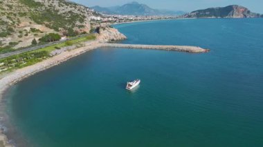 Balonlarla süslenmiş beyaz bir yat kayalık kıyılara ve manzaralı Alanya manzarasına yakın seyrediyor..