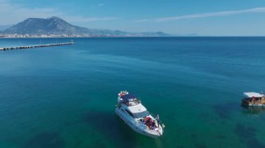 Yat pruvasında toplanan yolcular güneşli sahilin altında kutlama yapıyorlar..