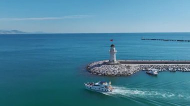 Uzaktaki dağlarla birlikte Alanya yakınlarında yelken açan beyaz bir yat..