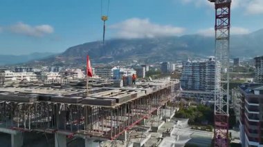 Yukarıdan: levhalar hizalandı, vinç yüklendi, güvenlik çalışanları aktif, ufuk çizgisi ve deniz kenarı görünür.