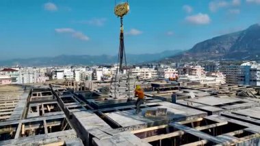 Turuncu miğferli adamlar levhaları toplayın, vinç kancasını görünür hale getirin, kıyı şeridini gerin.