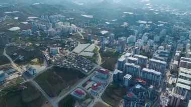 Yeşil tepeler ve deniz tarafından çerçevelenmiş modern daireler kıyı şeridi boyunca uzanır..